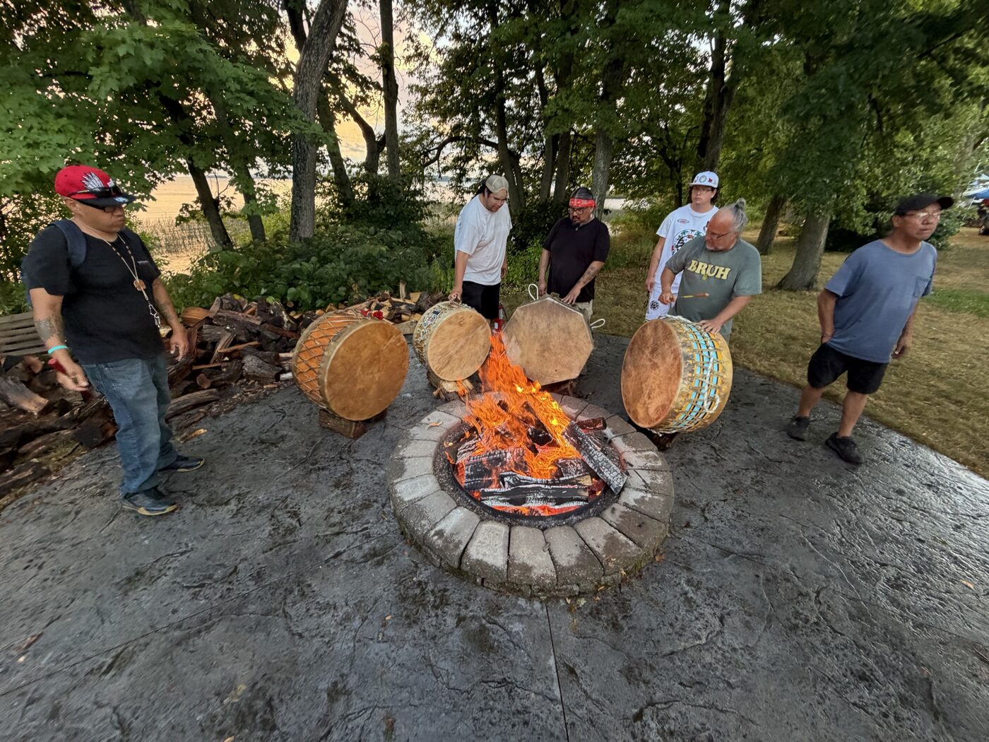 Drum keepers gathered around the fire with the lake behind