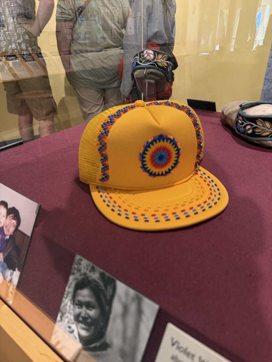 Beadwork medallion on a yellow trucker cap in a display case