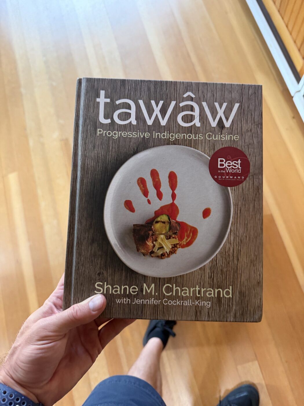 tawâw Progressive Indigenous Cuisine cookbook held in hand